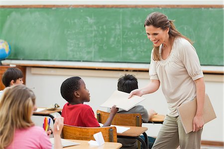 Elementary teacher collecting her students exercise books Stock Photo - Premium Royalty-Free, Code: 6109-06007538