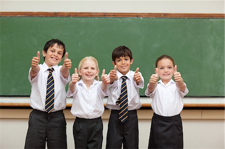 simsearch:6109-06007620,k - Smiling little children in school uniforms giving thumbs up Foto de stock - Royalty Free Premium, Número: 6109-06007620