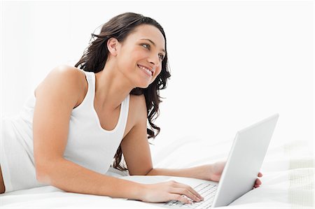 Young woman with her laptop on her bed Stock Photo - Premium Royalty-Free, Code: 6109-06194273