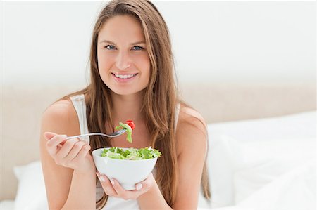 eating snack - Jeune femme souriante en mangeant une salade Photographie de stock - Premium Libres de Droits, Code: 6109-06194420