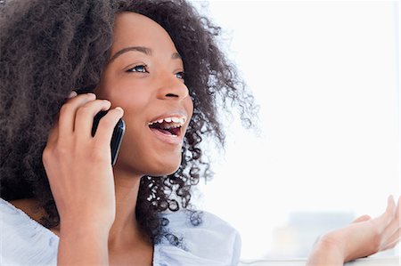 Close-up of a fuzzy hair woman talking on the phone Stock Photo - Premium Royalty-Free, Code: 6109-06194561