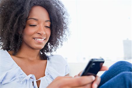 Close-up of a fuzzy hair woman texting Stock Photo - Premium Royalty-Free, Code: 6109-06194573