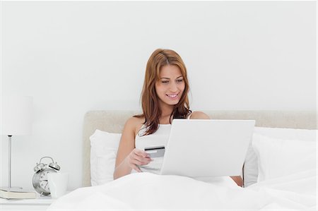 simsearch:6109-06194493,k - Rothaarige sitzen auf ihrem Bett mit ihrer Kreditkarte online Stockbilder - Premium RF Lizenzfrei, Bildnummer: 6109-06194504