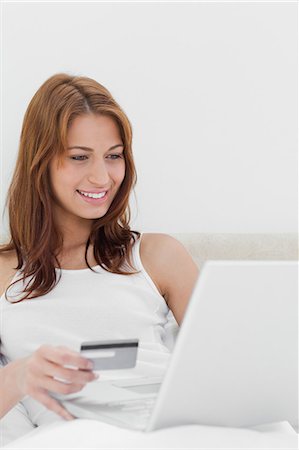 Redheaded sitting on her bed while shopping online Stock Photo - Premium Royalty-Free, Code: 6109-06194509