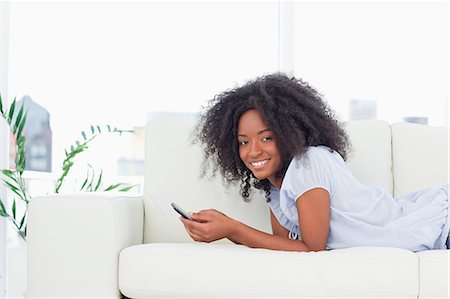 phone young woman caucasian sofa - Portrait of a cool brown woman texting Stock Photo - Premium Royalty-Free, Code: 6109-06194631
