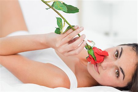 rose scent - Portrait d'une femme couchée sur le dos tout en sentant une rose Photographie de stock - Premium Libres de Droits, Code: 6109-06194988