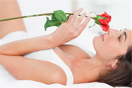 Woman lying on her back while smelling a rose Stock Photo - Premium Royalty-Free, Code: 6109-06194989