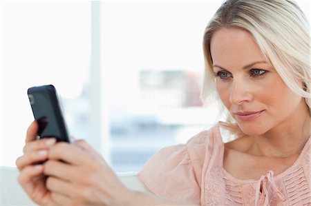 people looking at smartphone home not children - Close-up of a blonde texting on a sofa Stock Photo - Premium Royalty-Free, Code: 6109-06195012