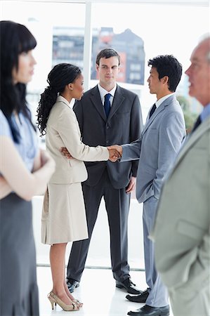Two business people shaking hands while the others are looking at them Foto de stock - Sin royalties Premium, Código: 6109-06195222