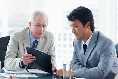 Serious businessman showing a clipboard to an employee Stock Photo - Premium Royalty-Free, Code: 6109-06195236