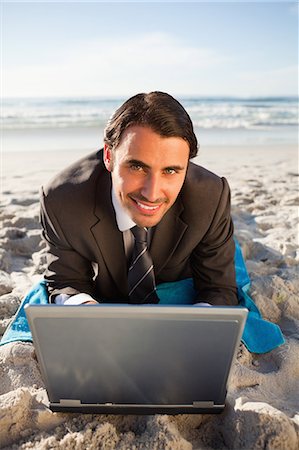 simsearch:6109-06195339,k - Jeune homme d'affaires souriant allongé sur une serviette de plage Photographie de stock - Premium Libres de Droits, Code: 6109-06195344