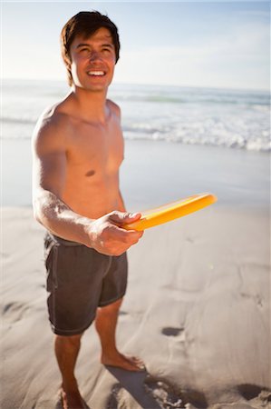 Handsome man playing frisbee in swimsuit Foto de stock - Sin royalties Premium, Código: 6109-06195369