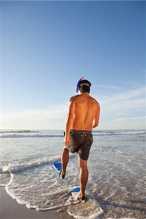 Jeune homme portant un équipement de plongée en apnée en marchant dans l'eau Photographie de stock - Premium Libres de Droits, Code: 6109-06195375