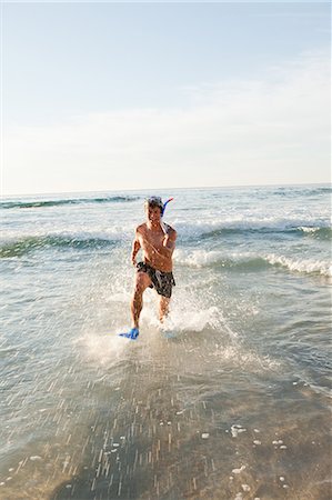 Jeune homme heureux en cours d'exécution dans l'eau avec palmes Photographie de stock - Premium Libres de Droits, Code: 6109-06195379