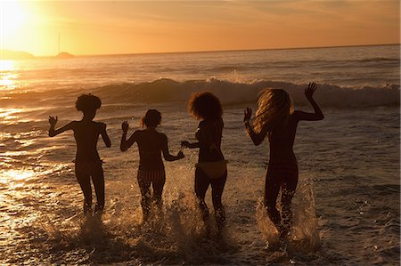 friends jumping outdoors - Four young women walking in the water together Stock Photo - Premium Royalty-Free, Code: 6109-06195391