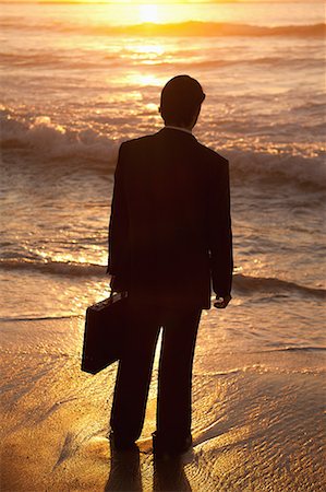 dark sky - Young businessman standing up on the beach at sunset Stock Photo - Premium Royalty-Free, Code: 6109-06195397