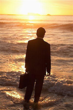 sunrise man back - Rear view of a young businessman standing in front of the ocean Stock Photo - Premium Royalty-Free, Code: 6109-06195398