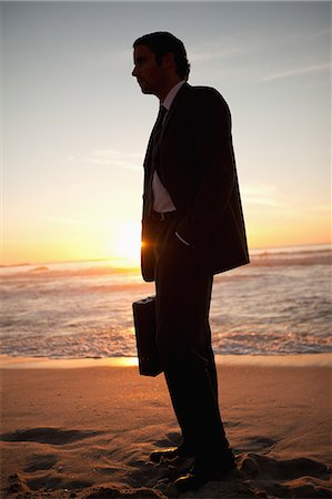 sand case - Young businessman looking far away while standing on the beach Stock Photo - Premium Royalty-Free, Code: 6109-06195400