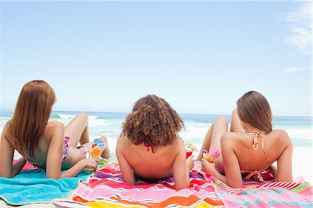 Three friends sunbathing while holding cocktails Stock Photo - Premium Royalty-Free, Code: 6109-06195597