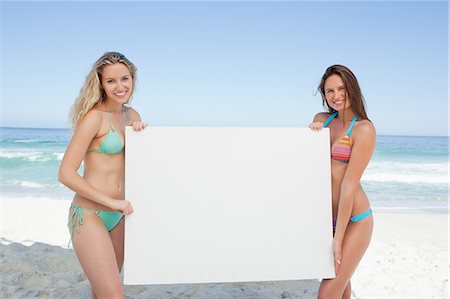 Two friends holding a blank poster by the sea Fotografie stock - Premium Royalty-Free, Codice: 6109-06195517