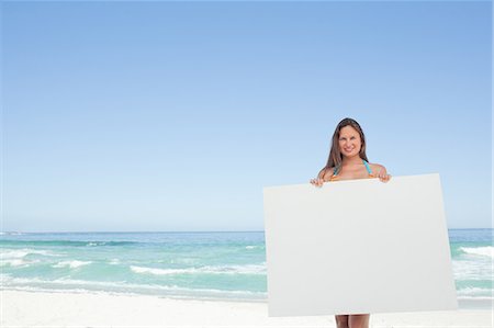 póster - Woman wearing a bikini holding a blank poster in front of her Foto de stock - Sin royalties Premium, Código: 6109-06195525