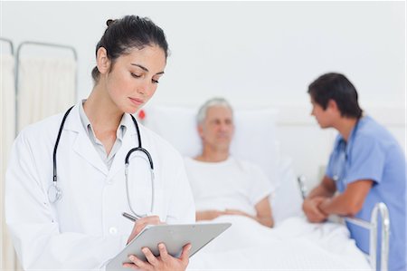 Serious doctor writing on a clipboard Stock Photo - Premium Royalty-Free, Code: 6109-06195668