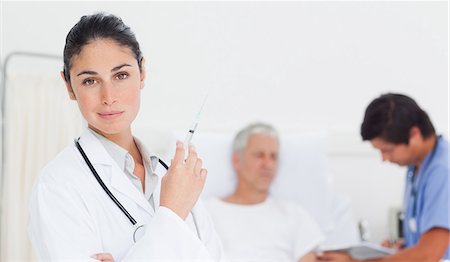 Doctor looking to her side while holding a syringe Foto de stock - Sin royalties Premium, Código: 6109-06195680