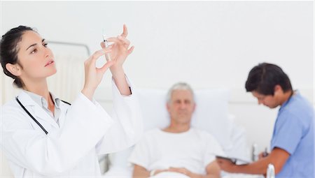 Female doctor examining a syringe Stock Photo - Premium Royalty-Free, Code: 6109-06195682