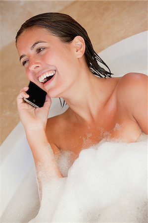 Laughing woman with her cellphone in the tub Stock Photo - Premium Royalty-Free, Code: 6109-06195752