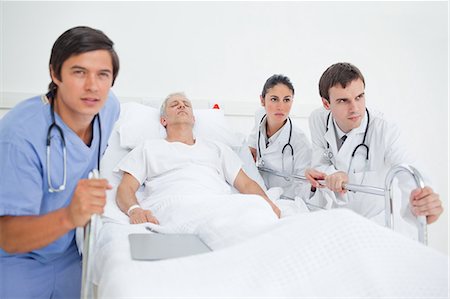 doctors pushing patient - Nurse and two doctors pushing a hospital bed Stock Photo - Premium Royalty-Free, Code: 6109-06195713