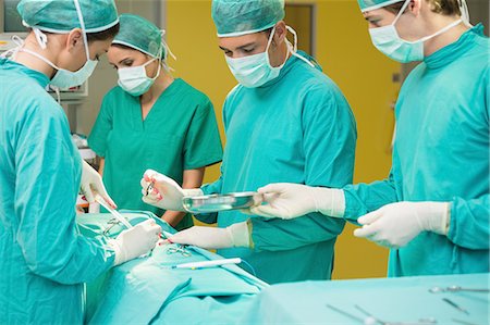 stern doctor - View of a male nurse giving a container to a surgeon Stock Photo - Premium Royalty-Free, Code: 6109-06195851