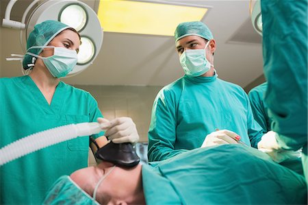 serious surgeon with mask - Surgeon looking at a monitor while operating Stock Photo - Premium Royalty-Free, Code: 6109-06195887