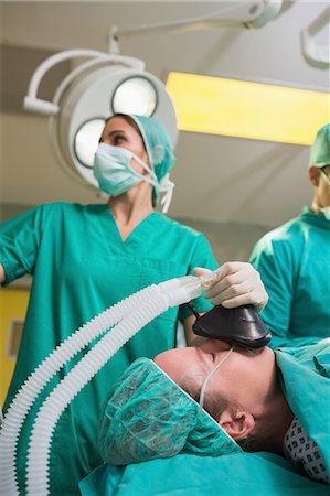 Anesthetist holding an oxygen mask while looking at monitor Foto de stock - Sin royalties Premium, Código: 6109-06195889