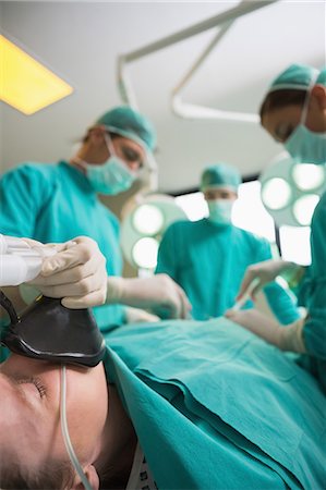 serious surgeon with mask - Focus on a patient lying on an operating table Stock Photo - Premium Royalty-Free, Code: 6109-06195894