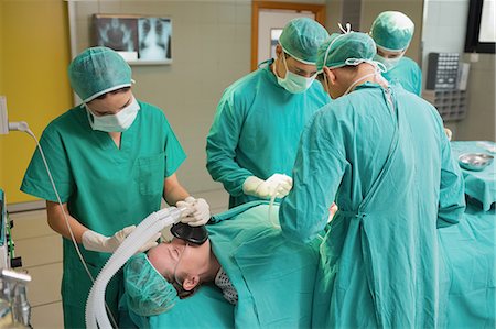 simsearch:6109-06195874,k - Patient lying on the operating table next to surgeons Foto de stock - Sin royalties Premium, Código: 6109-06195839