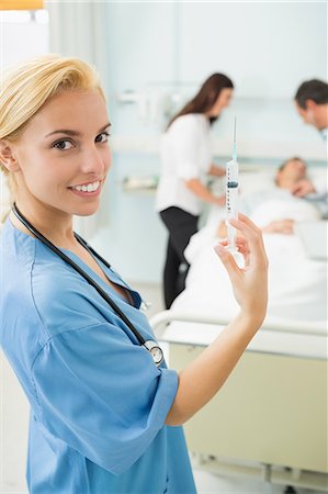Nurse looking at camera while holding a syringe Stock Photo - Premium Royalty-Free, Code: 6109-06195946