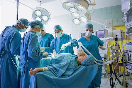 serious surgeon with mask - Group of surgeons operating an unconscious patient Stock Photo - Premium Royalty-Free, Code: 6109-06195965