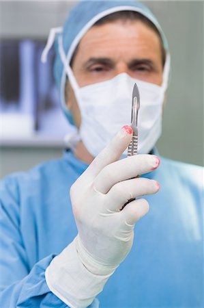 simsearch:6109-06196035,k - Surgeon holding a scalpel in his gloved hand Foto de stock - Royalty Free Premium, Número: 6109-06195974