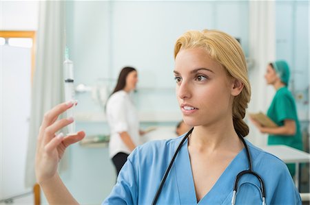 doctors inside the patients room photo - Blonde nurse holding a syringe Stock Photo - Premium Royalty-Free, Code: 6109-06195936