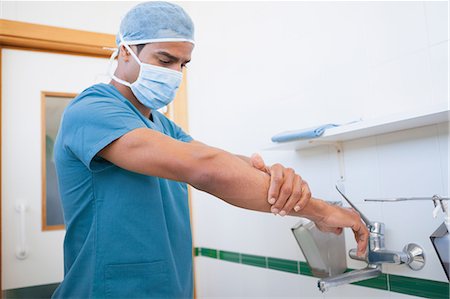 simsearch:6109-06196035,k - Surgeon with a surgical mask washing his hand Foto de stock - Royalty Free Premium, Número: 6109-06196038