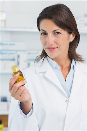simsearch:6109-08537870,k - Happy female pharmacist holding a bottle of pills in a pharmacy Stock Photo - Premium Royalty-Free, Code: 6109-06196154