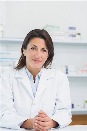 Female pharmacist behind a counter joining his hands Foto de stock - Sin royalties Premium, Código: 6109-06196155