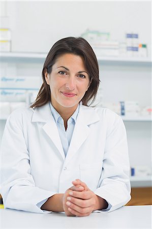 simsearch:6109-06196195,k - Woman pharmacist behind a counter joining her hands Stock Photo - Premium Royalty-Free, Code: 6109-06196156