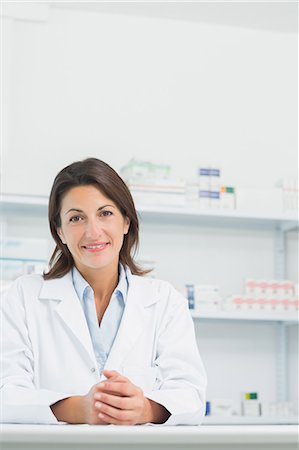 simsearch:6109-06196243,k - Smiling woman pharmacist joining her hands on a counter Stock Photo - Premium Royalty-Free, Code: 6109-06196159