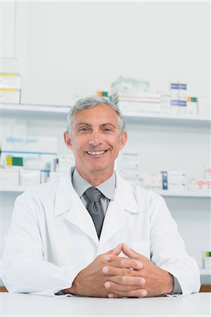 pharmacist looking at camera - Smiling male pharmacist with his hands joined on a counter Stock Photo - Premium Royalty-Free, Code: 6109-06196166