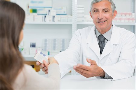 simsearch:6109-06196218,k - Smiling pharmacist giving pills to a customer Stock Photo - Premium Royalty-Free, Code: 6109-06196182