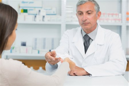 Male pharmacist receiving a prescription from a customer Stock Photo - Premium Royalty-Free, Code: 6109-06196185