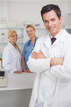 pharmacist looking at camera - Pharmacist in a pharmacy with colleagues Stock Photo - Premium Royalty-Free, Code: 6109-06196101