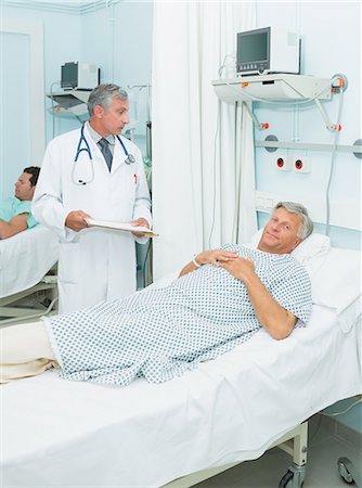 simsearch:6109-06196338,k - Doctor talking to a patient in a bed ward Stock Photo - Premium Royalty-Free, Code: 6109-06196253