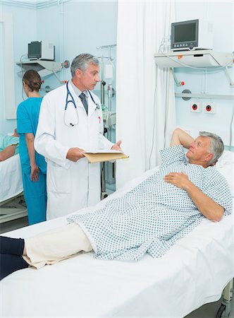 simsearch:6109-06196338,k - Doctor talking with a patient in a bed ward Stock Photo - Premium Royalty-Free, Code: 6109-06196252